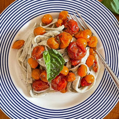 Roasted tomatoes with fettuccine in a blue and white striped bowl by Caskata