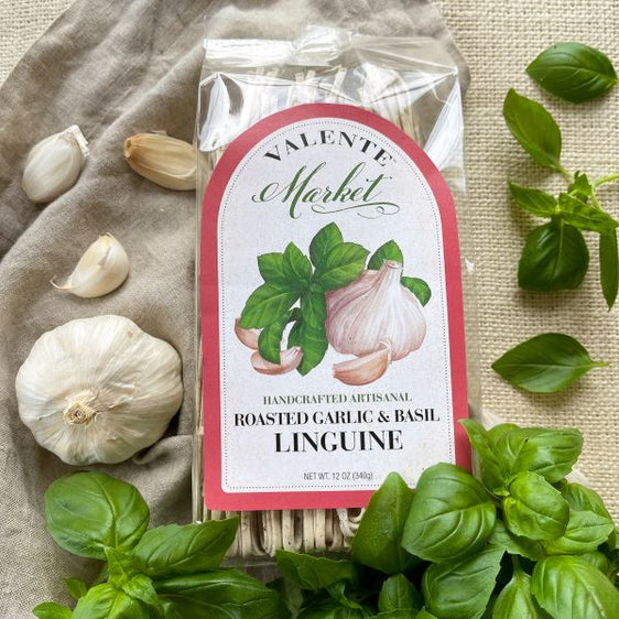 Roasted garlic and basil linguine in a clear bag depicted with fresh garlic and fresh basil and a rose colored border on the label.l
