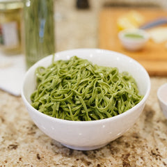 Bowl of cooked spinach linguine in a white bowl