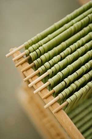 Spinach fettuccine drying on wooden dowel rod rack