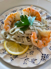 Garlic parsley fettuccine and shrimp cooked on a blue and white plate